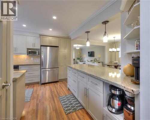 This kitchen features wood flooring, recessed lighting, and a kitchen island with a granite countertop and pendant lighting - 42 Culpepper Drive, Waterloo, ON - Indoor Photo Showing Kitchen With Upgraded Kitchen
