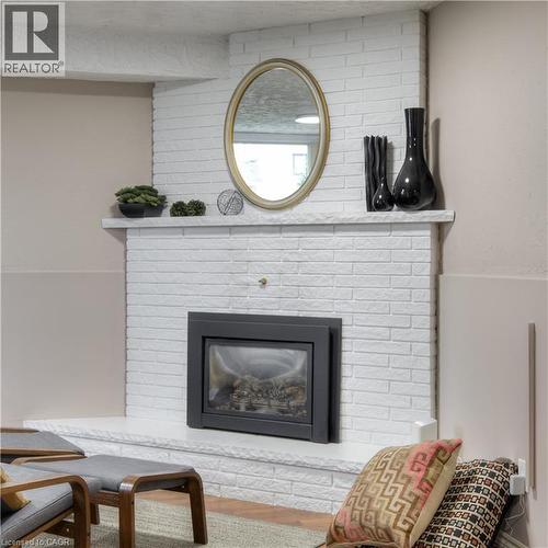 Living area featuring a white painted brick fireplace with a black firebox insert and a white mantel - 42 Culpepper Drive, Waterloo, ON - Indoor Photo Showing Living Room With Fireplace