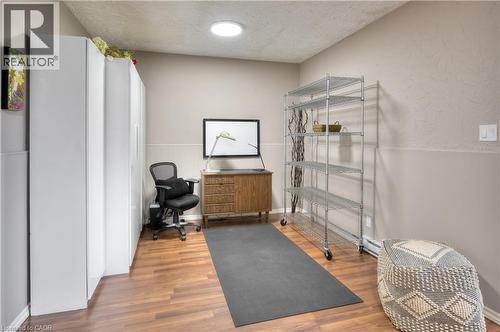 This versatile room features warm-toned flooring, neutral painted walls, and a circular ceiling light fixture - 42 Culpepper Drive, Waterloo, ON - Indoor