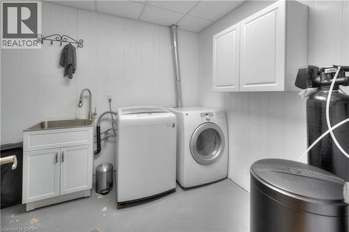 This utility area features white paneled walls, a stainless steel sink with a modern faucet, and white cabinetry - 42 Culpepper Drive, Waterloo, ON - Indoor Photo Showing Laundry Room
