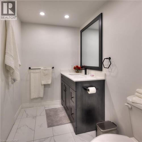 Bathroom featuring a dark wood vanity with a white countertop and sink, a large mirror with a dark frame, and white tiled flooring - 42 Culpepper Drive, Waterloo, ON - Indoor Photo Showing Bathroom