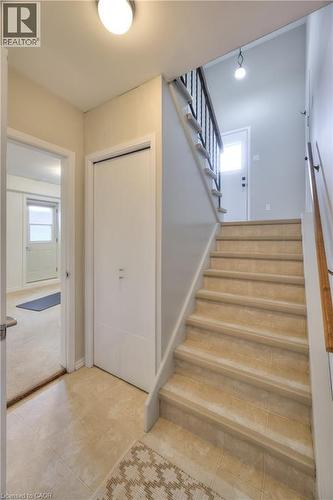Entryway featuring light-colored tile flooring, a staircase with a dark metal railing, and a white closet door - 42 Culpepper Drive, Waterloo, ON - Indoor Photo Showing Other Room