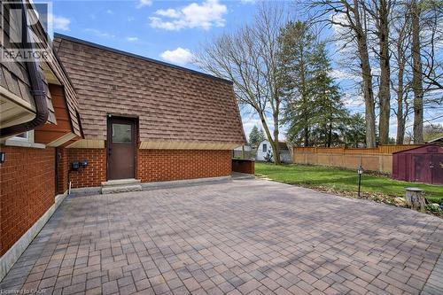 The property features extensive brickwork, a brown shingled roof, and a paved patio area - 42 Culpepper Drive, Waterloo, ON - Outdoor