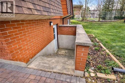 The property features a red brick exterior, a tiered roof, and a concrete staircase leading to a white door - 42 Culpepper Drive, Waterloo, ON - Outdoor