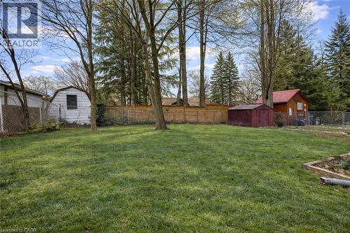 The property offers a spacious yard with a lush lawn, established trees, and a wooden fence - 42 Culpepper Drive, Waterloo, ON - Outdoor