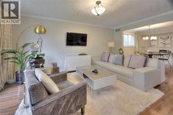 The living area features hardwood flooring, a ceiling-mounted light fixture, and crown molding - 