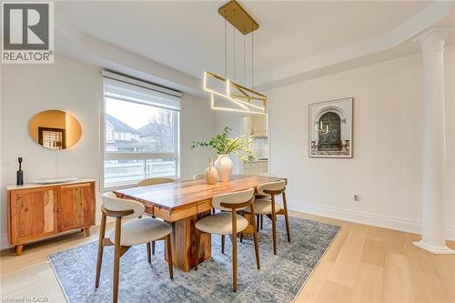 Dining area featuring light hardwood flooring, a contemporary chandelier, and a large window providing natural light - 4267 Sarazen Drive, Burlington, ON - Indoor Photo Showing Dining Room