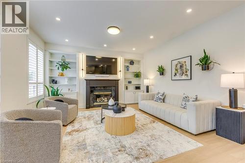 Living area with light hardwood flooring, a fireplace with a dark mantel, and built-in shelving - 4267 Sarazen Drive, Burlington, ON - Indoor Photo Showing Living Room With Fireplace