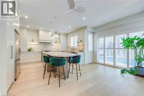 The property features a kitchen with light-colored flooring, an island with seating, stainless steel appliances, and ample cabinetry - 4267 Sarazen Drive, Burlington, ON - Indoor