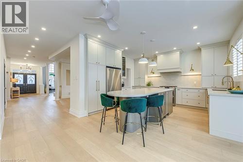 The property features a bright kitchen with white cabinetry, a large island with a countertop, and stainless steel appliances - 4267 Sarazen Drive, Burlington, ON - Indoor Photo Showing Kitchen With Upgraded Kitchen