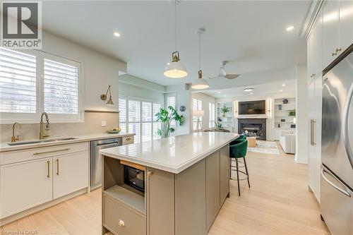 The kitchen features a large island with a light-colored countertop, stainless steel appliances, and a sink with a gold-toned faucet - 4267 Sarazen Drive, Burlington, ON - Indoor Photo Showing Kitchen With Upgraded Kitchen