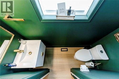 The bathroom features a white toilet and a white vanity with a rectangular basin, complemented by gold-toned fixtures - 4267 Sarazen Drive, Burlington, ON - Indoor Photo Showing Other Room