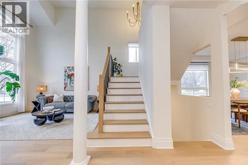 The property features an open-concept layout with light-colored flooring, a staircase with light wood treads and a dark railing, and a living area with large arched windows providing ample natural lig - 4267 Sarazen Drive, Burlington, ON - Indoor Photo Showing Other Room