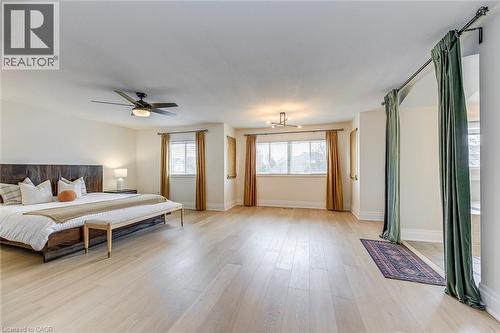 Spacious room featuring light wood flooring, white walls, and multiple windows with blinds and curtains - 4267 Sarazen Drive, Burlington, ON - Indoor
