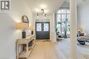 Elegant entryway featuring light hardwood floors, a modern chandelier, and double dark doors with glass inserts - 4267 Sarazen Drive, Burlington, ON  - Indoor Photo Showing Other Room 