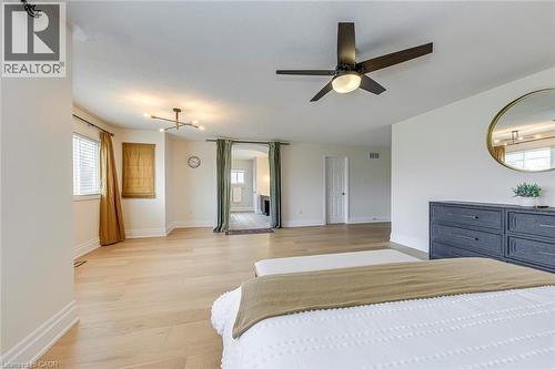 Bright interior room featuring light-toned hardwood flooring, white walls, and a contemporary ceiling fan - 4267 Sarazen Drive, Burlington, ON - Indoor Photo Showing Bedroom