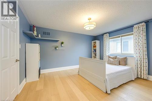 This room features light hardwood flooring, a ceiling-mounted light fixture, and a window providing natural light - 4267 Sarazen Drive, Burlington, ON - Indoor Photo Showing Bedroom