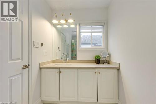 Bathroom vanity featuring a light-colored countertop, an integrated sink with a chrome faucet, and white cabinetry - 4267 Sarazen Drive, Burlington, ON - Indoor Photo Showing Bathroom