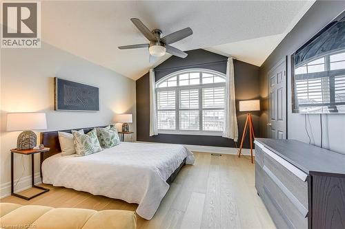 This room features a vaulted ceiling, light wood flooring, an arched window with blinds, and a ceiling fan - 4267 Sarazen Drive, Burlington, ON - Indoor Photo Showing Bedroom