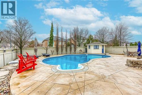 The property features a backyard swimming pool with a shaped concrete surround - 4267 Sarazen Drive, Burlington, ON - Outdoor With In Ground Pool With Deck Patio Veranda