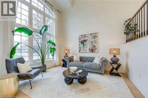 Bright living area featuring a vaulted ceiling, a large arched window with grid detailing, and light hardwood floors - 4267 Sarazen Drive, Burlington, ON - Indoor Photo Showing Living Room