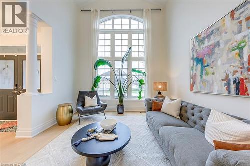 This living space features a large arched window with grid detailing, tall ceilings, and light-toned flooring - 4267 Sarazen Drive, Burlington, ON - Indoor Photo Showing Living Room