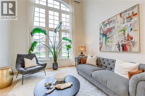 Living area featuring a large arched window with multiple panes, providing natural light, and light-colored flooring - 4267 Sarazen Drive, Burlington, ON - Indoor Photo Showing Living Room