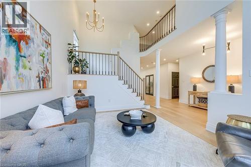 The property features a spacious living area with high ceilings, hardwood flooring, and a grand staircase with dark metal railings - 4267 Sarazen Drive, Burlington, ON - Indoor Photo Showing Living Room