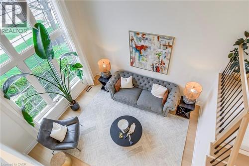 This inviting living area features high ceilings, expansive windows providing abundant natural light, and light-toned hardwood flooring - 4267 Sarazen Drive, Burlington, ON - Indoor