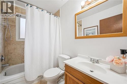Bathroom featuring a vanity with a white countertop and a wooden base, a mirror with a wooden frame, and a shower area with tiled walls - 217 Johanna Drive, Cambridge, ON - Indoor Photo Showing Bathroom
