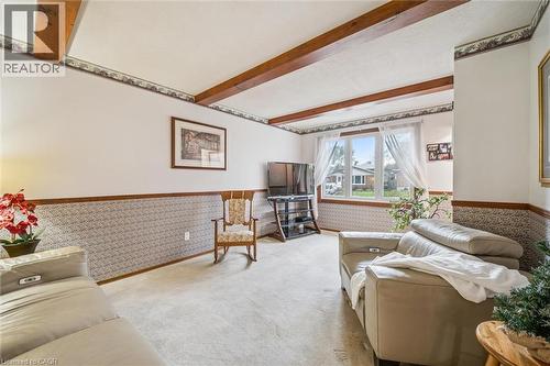 Living room featuring carpeted floors, exposed ceiling beams, and a large window providing views of the outdoors - 217 Johanna Drive, Cambridge, ON - Indoor