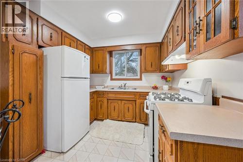 The kitchen features wood cabinetry, a white refrigerator, a white gas range, and a window above the sink - 217 Johanna Drive, Cambridge, ON - Indoor Photo Showing Kitchen With Double Sink