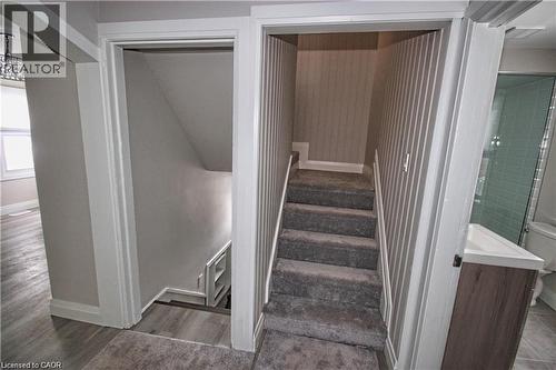 The property features a staircase with carpeted steps and striped wallpaper, a bathroom with a glass-enclosed shower, and a vanity with a white countertop - 1356 Upper Wellington Street, Hamilton, ON - Indoor Photo Showing Other Room