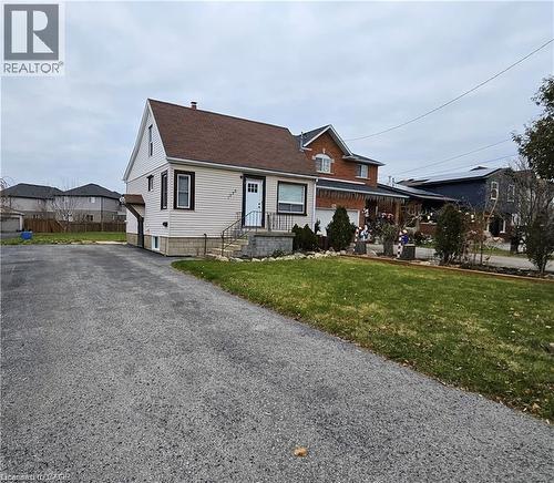 The property features a brown roof and light-colored siding with dark trim, set on a lot with a paved driveway and a lawn - 1356 Upper Wellington Street, Hamilton, ON - Outdoor