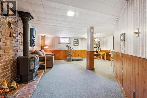 This versatile space features a brick accent wall with a stove, carpeted flooring, and a drop ceiling - 155 Hungerford Road, Cambridge, ON - Indoor Photo Showing Other Room