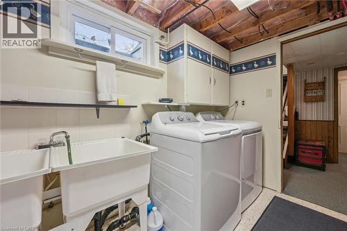 The property features a laundry area with a white washing machine and dryer, a double utility sink, and wall-mounted cabinetry - 155 Hungerford Road, Cambridge, ON - Indoor Photo Showing Laundry Room