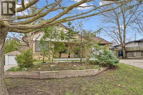 The property features a front yard with a raised garden bed, mature trees, and a detached garage with a white garage door - 155 Hungerford Road, Cambridge, ON - Outdoor