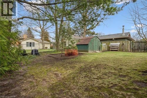 The property features a spacious yard with a green storage shed, a wooden fence, and mature trees - 155 Hungerford Road, Cambridge, ON - Outdoor