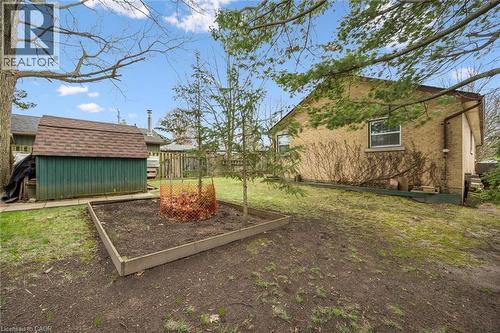 The property includes an exterior storage shed with a shingled roof, a raised garden bed, and a spacious yard with mature trees - 155 Hungerford Road, Cambridge, ON - Outdoor