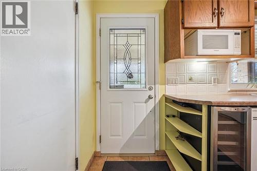 The property features a door with decorative glass, tile flooring, and a kitchen area with wood cabinetry, a microwave, and a beverage cooler - 155 Hungerford Road, Cambridge, ON - Indoor