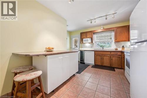 The kitchen features tile flooring, wood cabinetry, track lighting, and a white refrigerator - 155 Hungerford Road, Cambridge, ON - Indoor Photo Showing Kitchen