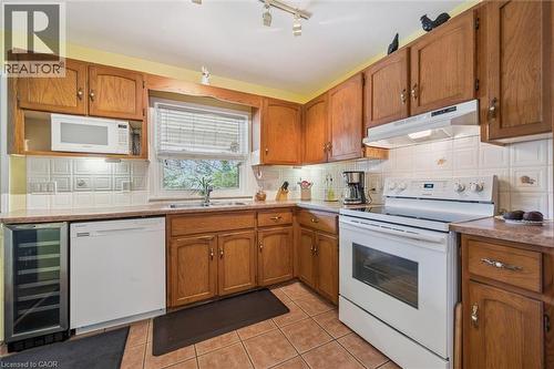 The kitchen features wood cabinetry, a white tile backsplash, and a window above the sink - 155 Hungerford Road, Cambridge, ON - Indoor Photo Showing Kitchen With Double Sink