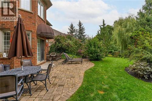 The property features a brick exterior, a paved patio area, and a lush green lawn - 4278 Clubview Drive, Burlington, ON - Outdoor With Deck Patio Veranda