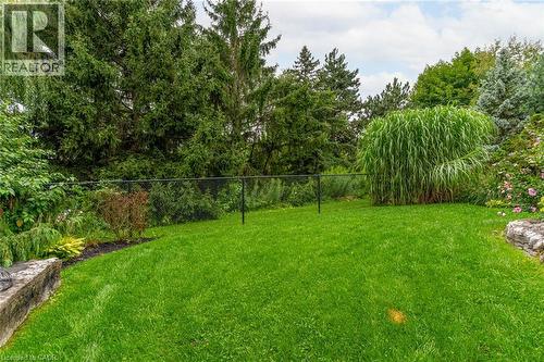 The property features a spacious yard with a lush green lawn, mature trees, and well-maintained garden beds - 4278 Clubview Drive, Burlington, ON - Outdoor