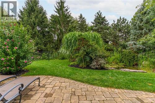 The property features an extensive yard with a paved patio, a lush lawn, and mature trees - 4278 Clubview Drive, Burlington, ON - Outdoor