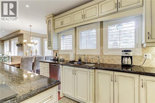 The kitchen features granite countertops, custom cabinetry, a tile backsplash, and stainless steel sink - 4278 Clubview Drive, Burlington, ON - Indoor Photo Showing Kitchen With Double Sink With Upgraded Kitchen