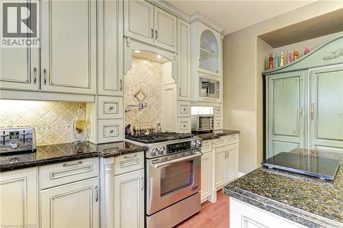 The kitchen features extensive cream-colored cabinetry, dark granite countertops, and a stainless steel oven range - 4278 Clubview Drive, Burlington, ON - Indoor Photo Showing Kitchen With Upgraded Kitchen