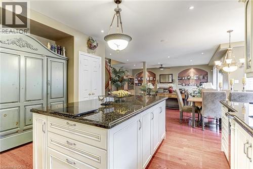 The kitchen features a large island with a dark granite countertop, light-colored cabinetry, and hardwood flooring - 4278 Clubview Drive, Burlington, ON - Indoor Photo Showing Kitchen With Upgraded Kitchen
