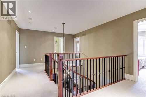 Spacious landing area featuring neutral-toned walls, recessed lighting, and a chandelier, with carpeted flooring and a staircase with a dark wood handrail and black spindles - 4278 Clubview Drive, Burlington, ON - Indoor Photo Showing Other Room