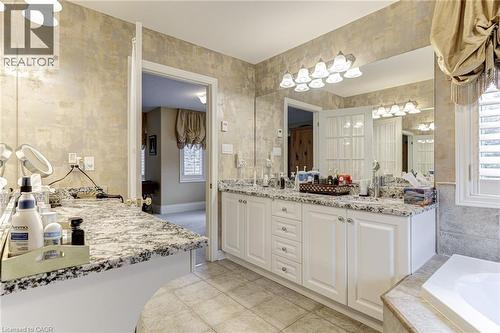 The bathroom features a double vanity with white cabinetry, granite countertops, and a large mirror with integrated lighting - 4278 Clubview Drive, Burlington, ON - Indoor Photo Showing Bathroom